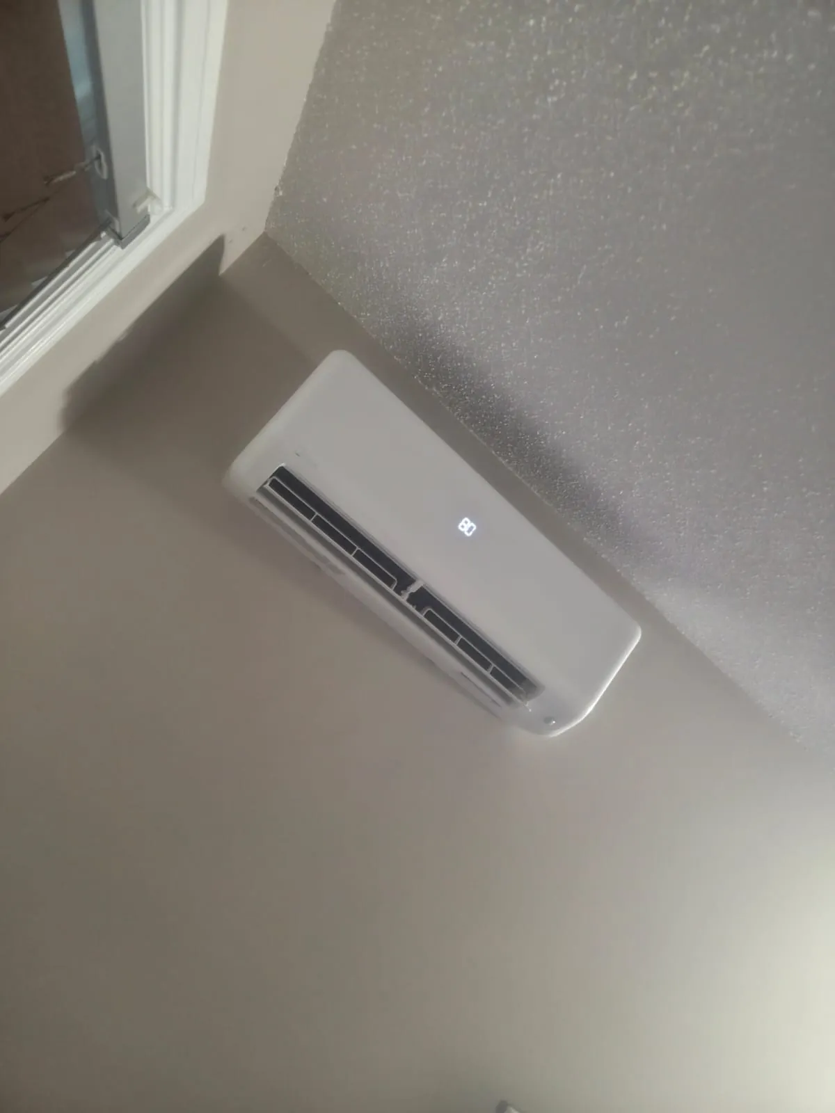 Ductless wall unit beside a window, seen from below