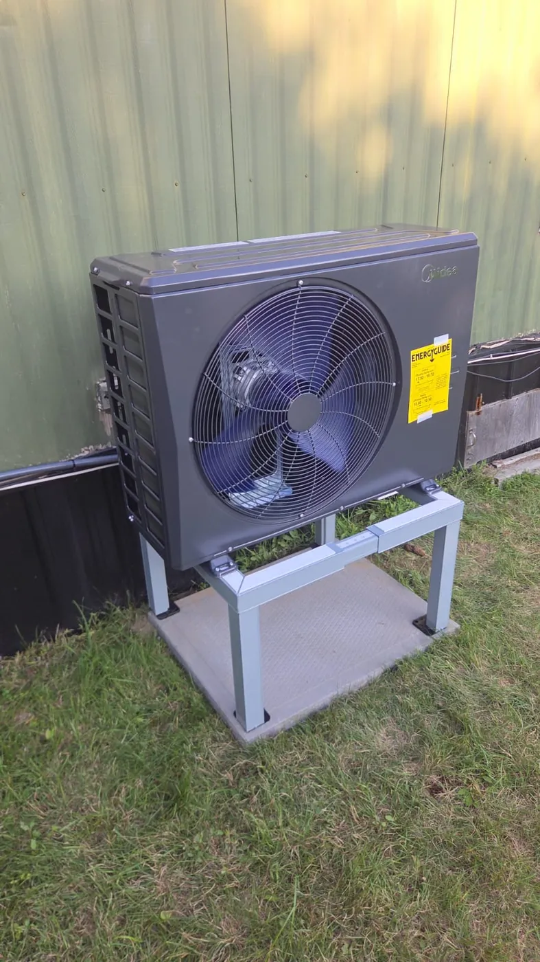 Midea cold-climate heat pump on a stand above the lawn