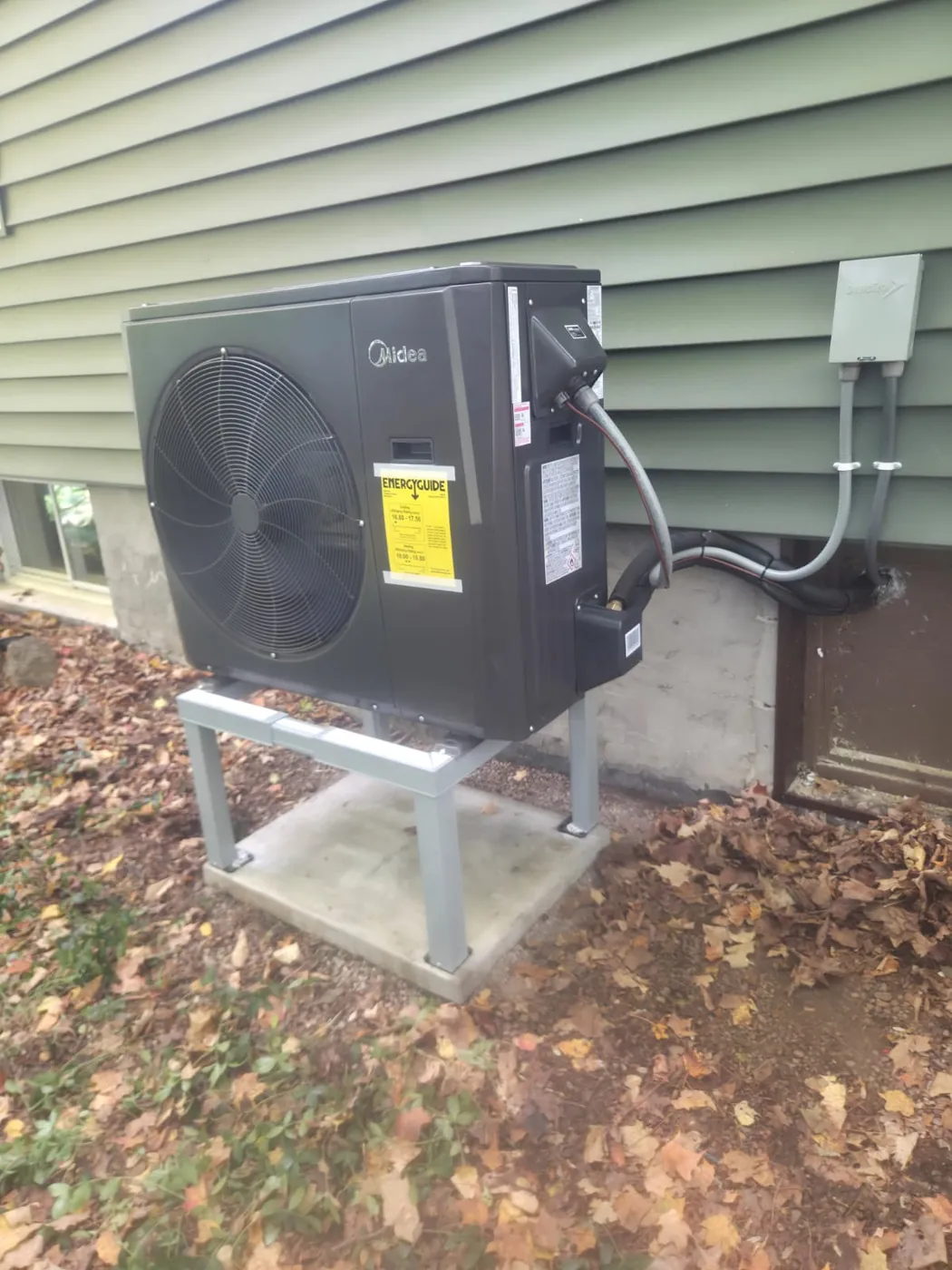 Midea cold-climate heat pump installed beside green siding