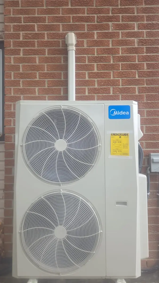 Large Midea multi-zone outdoor unit against a brick wall