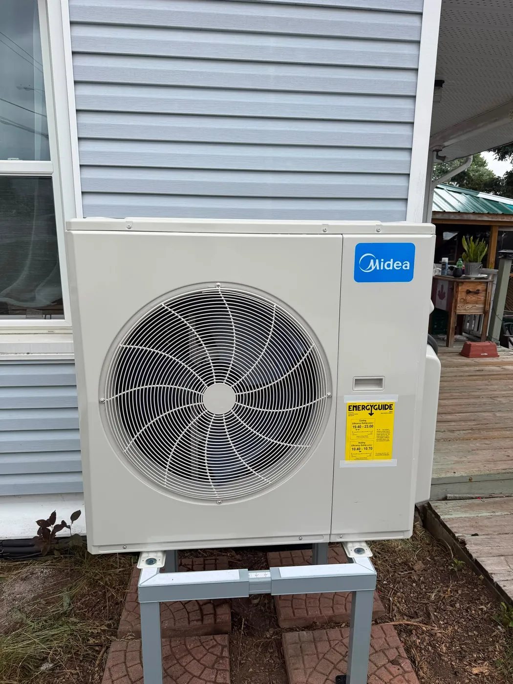 Midea outdoor unit on a stand next to a deck