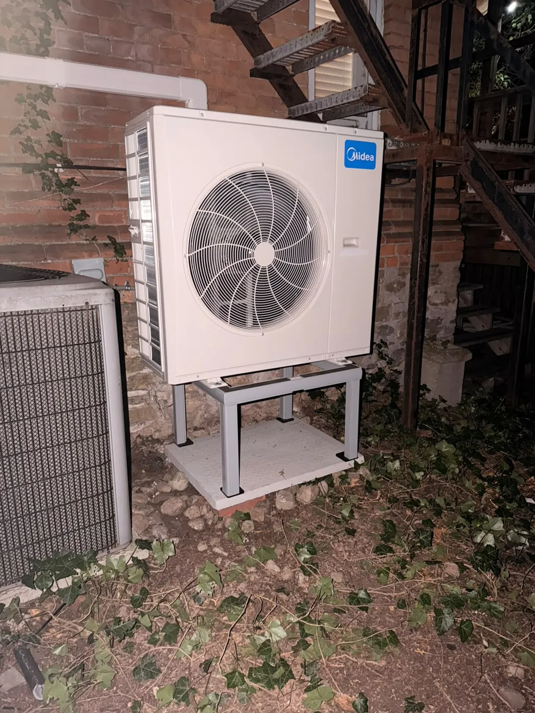 Midea outdoor unit on a stand beside the older condenser it replaced