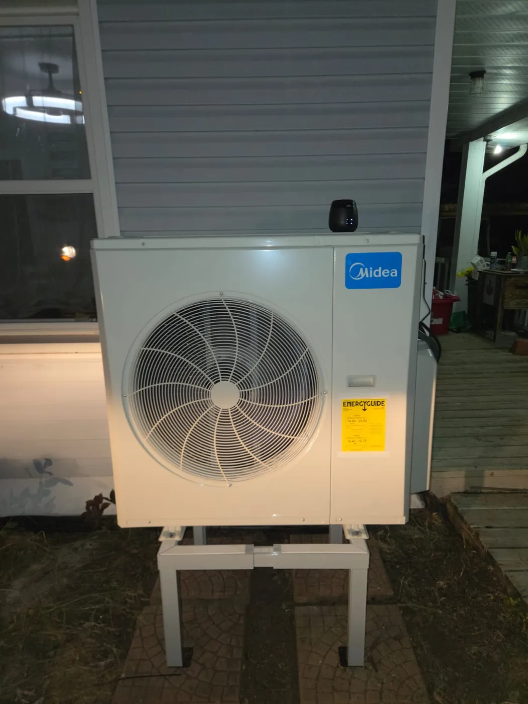 Midea outdoor unit on a stand next to a covered porch