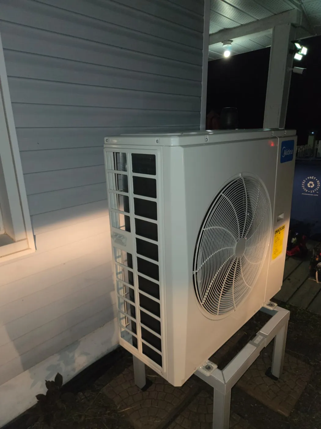 Side view of a Midea outdoor unit on a raised stand