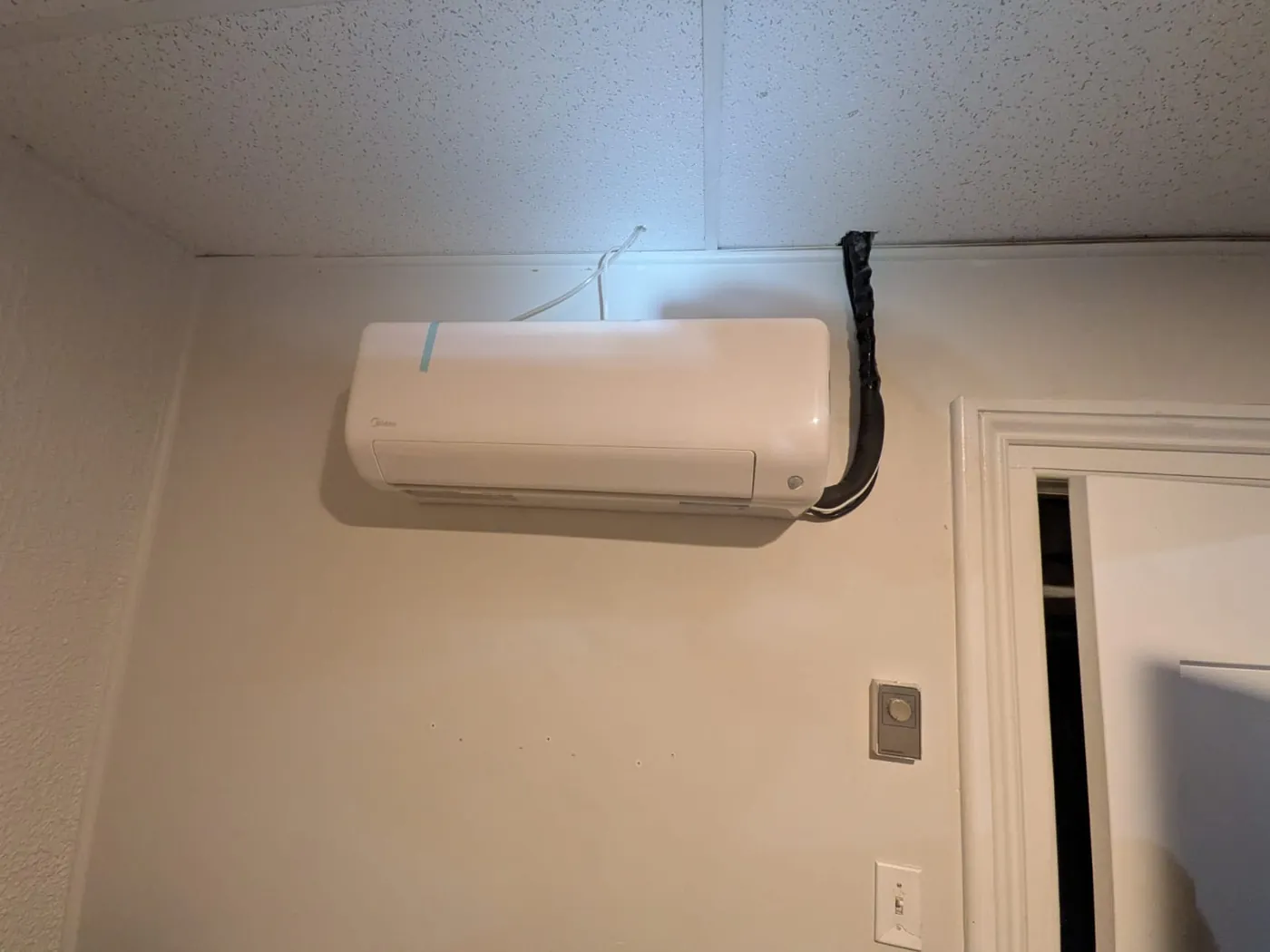 Midea ductless head mounted near the ceiling in a finished room