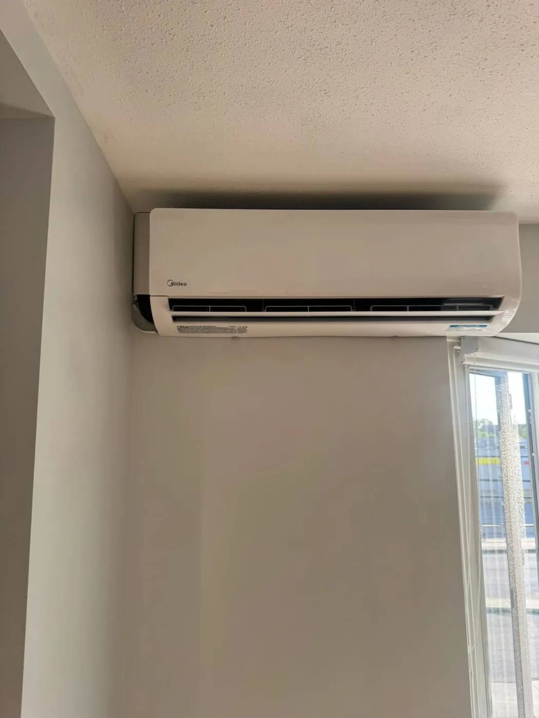 Midea ductless head in a corner beside a patio door