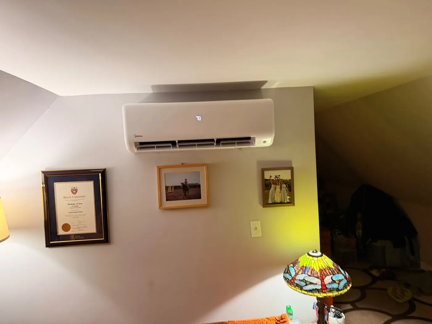 Midea ductless wall head above framed photos in a living room